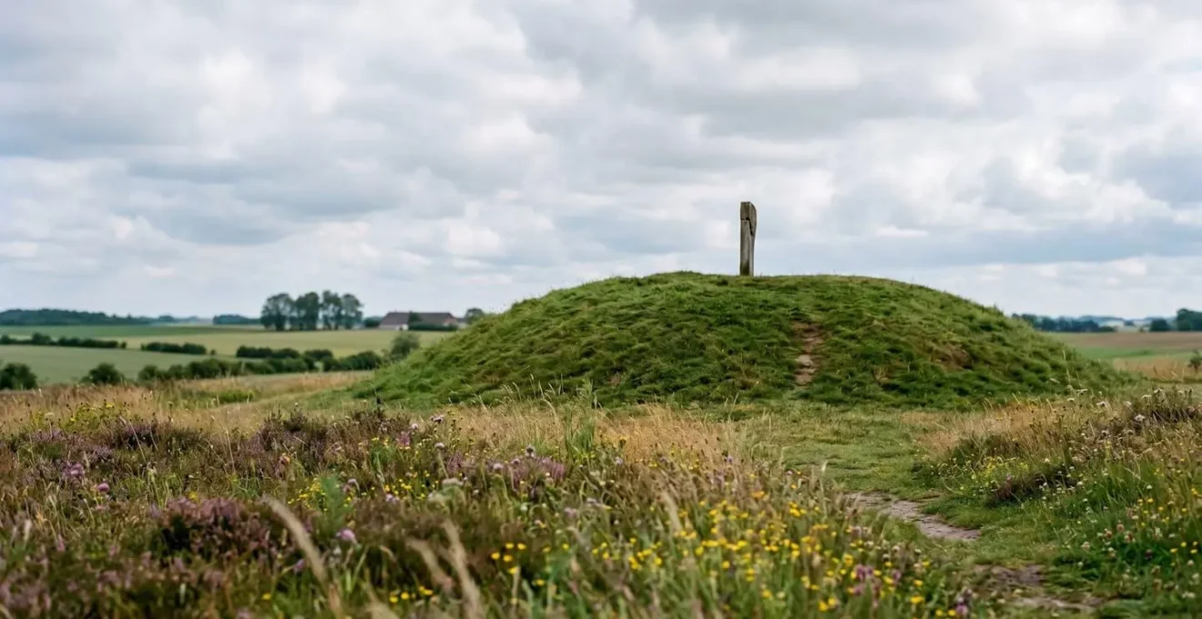 Rolling Danish countryside with ancient grass-covered burial mound under soft natural light