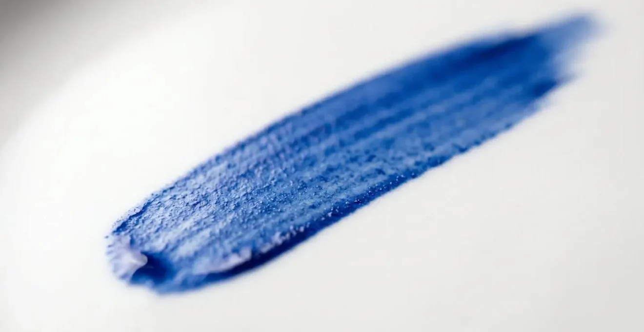 Macro view of cobalt blue brushstroke on white porcelain surface showing hand-painted texture