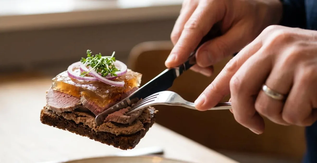 Detailed cross-section view showing distinct layers of liver pate, salt beef, aspic, and onion rings on dark rye bread